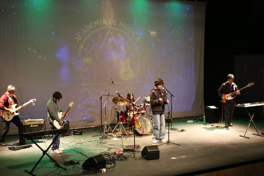 Banda completa tocando en el escenario de la academia