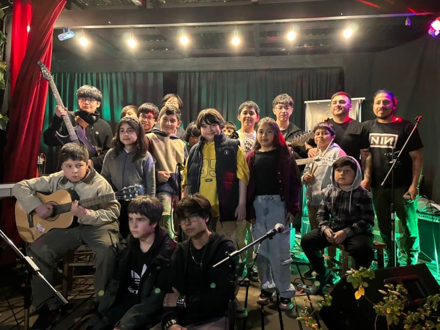 Foto grupal de alumnos y profesores en un bar con cortina roja