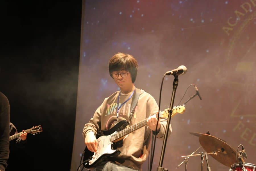 Alumno con guitarra eléctrica y anteojos