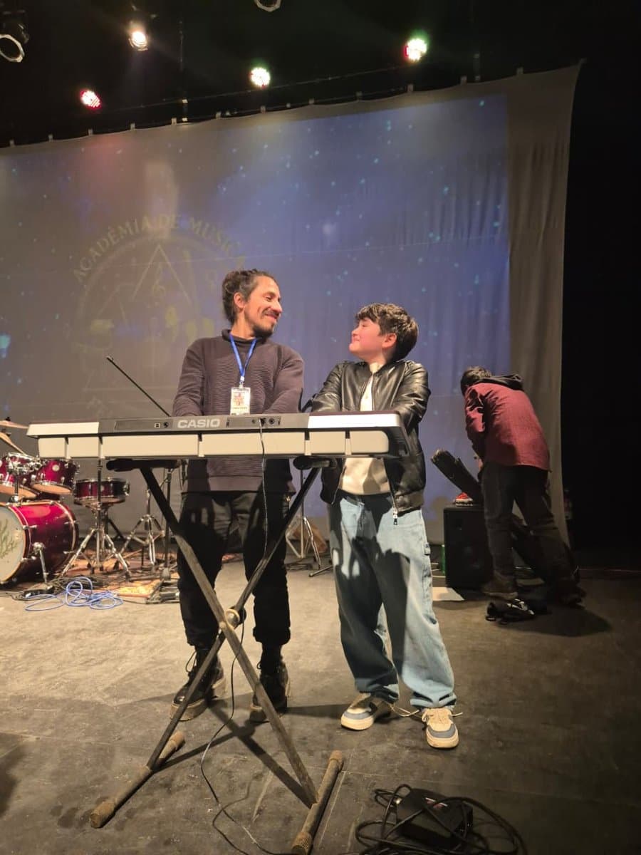 Profesor y alumno sonriendo junto a un teclado
