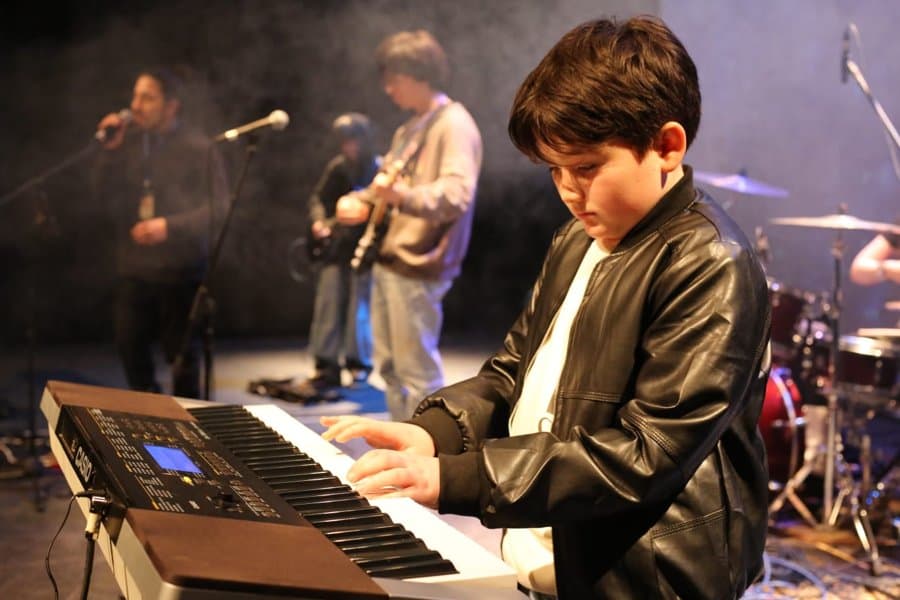 Alumno con chaqueta de cuero tocando teclado