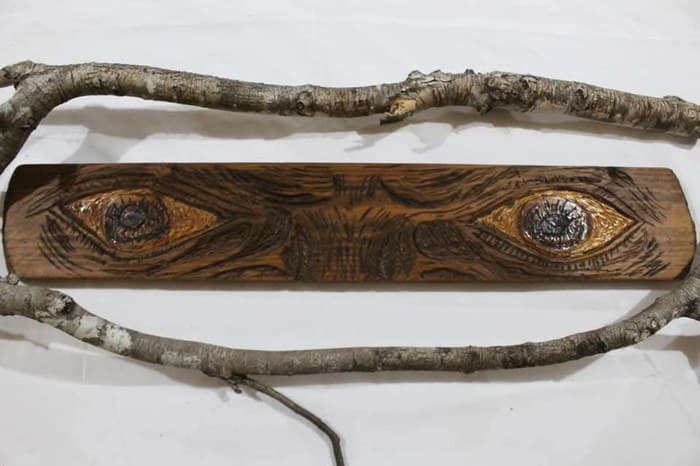 Tallado en madera de una placa con un par de ojos estilizados